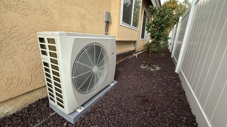 Outdoor heat-pump unit beside fence