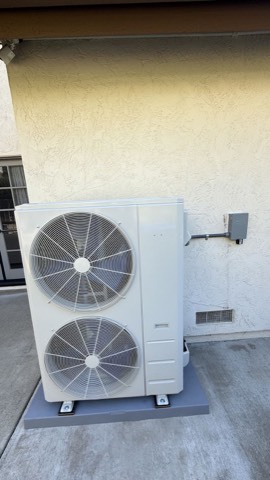 New dual-fan condenser on stucco wall