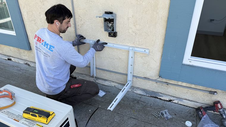 Technician mounting mini-split wall bracket