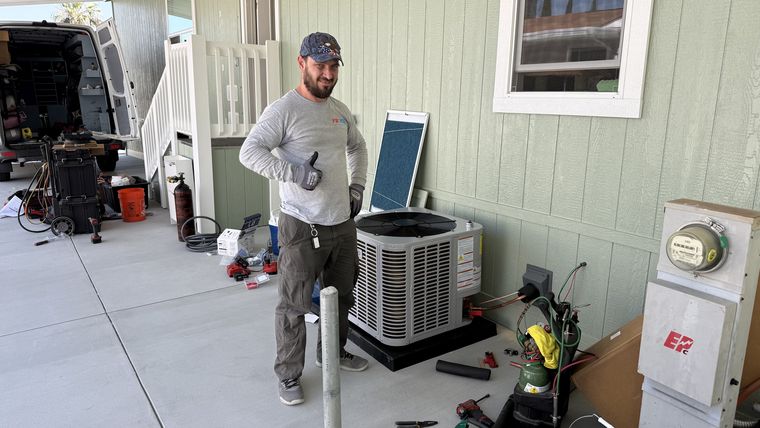 Technician thumbs-up beside new AC condenser